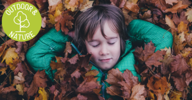 child laying in leaves