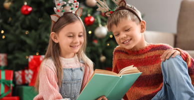 A boy and girl reading a book at christmas