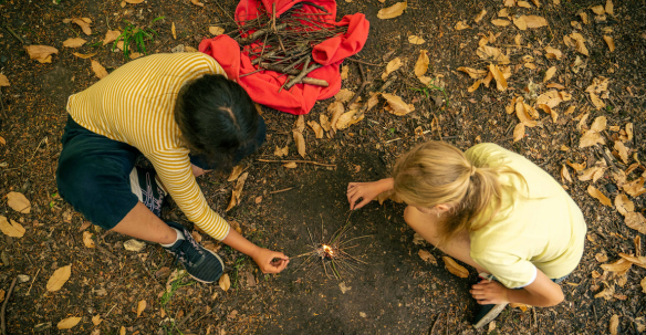 Two children lighting a fire in the woods