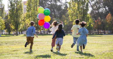 Children running in the park with balloons