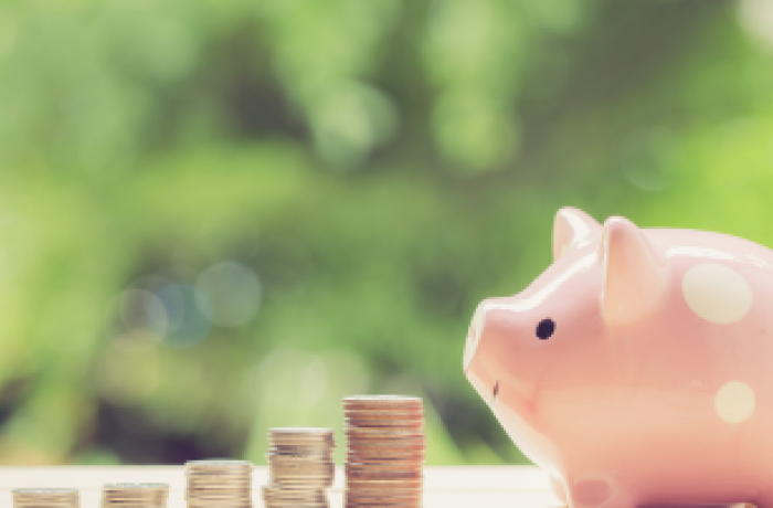 Coin stacked next to a pink piggy bank