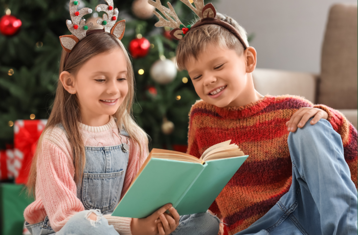 a girl and boy reading a book at christmas